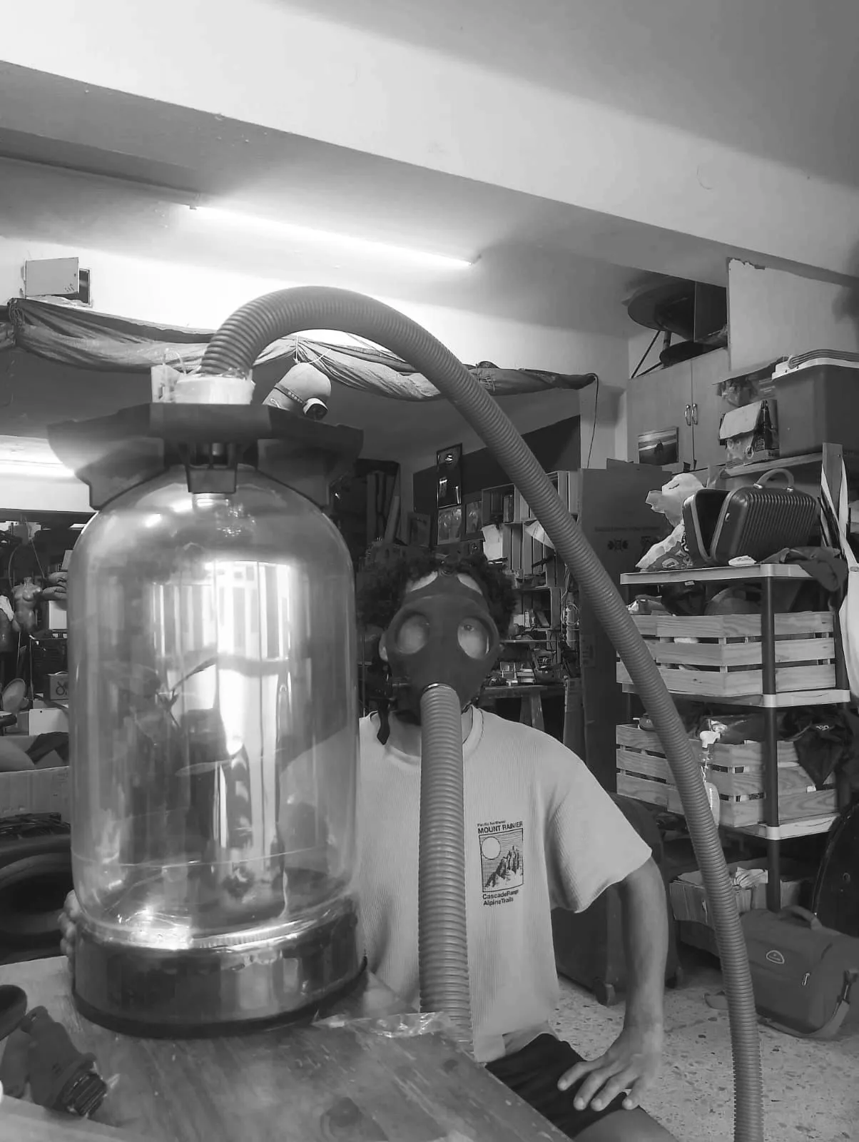 Una persona se agacha en un suelo oscuro, con ropa brillante y holgada. Una luz azul proyecta sombras en la pared.